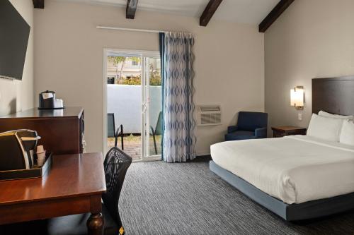 a hotel room with a bed and a desk and a window at Cannery Row Inn in Monterey