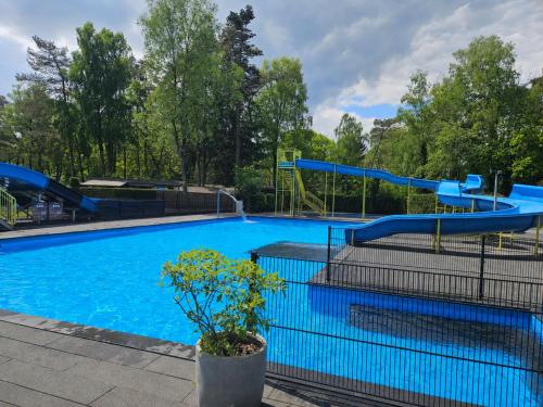 ein Schwimmbad mit Rutsche in einem Park in der Unterkunft Roosje in Hoenderloo