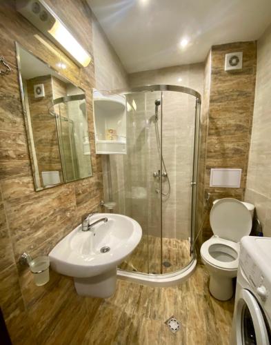 a bathroom with a shower and a sink and a toilet at Апартамент Green Lines in Primorsko