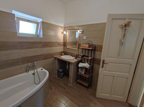 a bathroom with a tub and a sink and a mirror at Vazsita ház in Erdőbénye