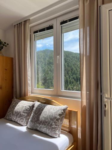 a bed with a pillow in front of a window at Adamov Konak Apartmani in Lazići