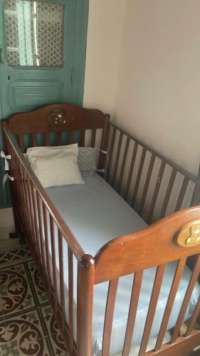 a wooden crib with a mattress in a room at Beit Emna3 in Kairouan