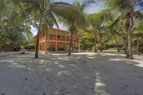 a building with palm trees in front of it at Charming 2BR Beach House Ideal for Extended Stays in Placencia