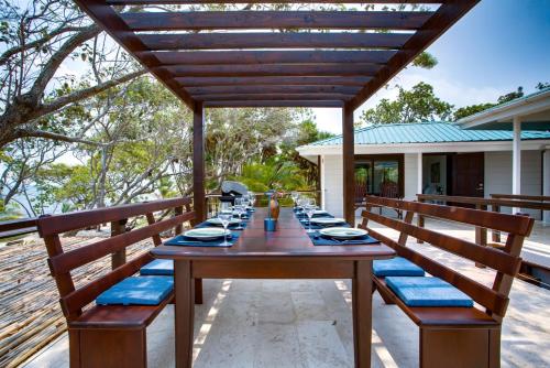 a wooden table with blue seats on a patio at Picture-Perfect 2-Bedroom Oceanfront Home w Pool in Placencia