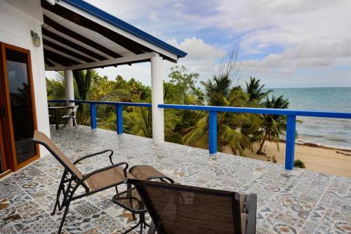 a balcony with two chairs and the ocean at Beachfront 3-Bed, 2-Bath Family Getaway with Pool in Placencia