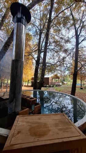 a wooden table sitting next to a pond with trees at Refugio El Rocio lodge tinaja,piscina,bosque in Nacimiento