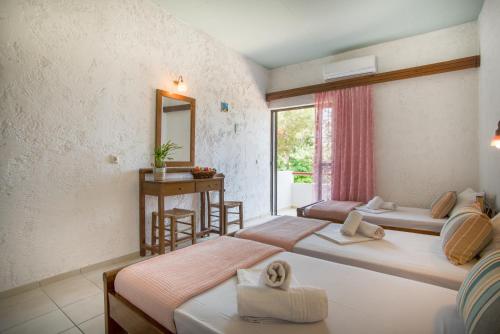 a bedroom with two beds and a desk and a window at Violetta Hotel in Amoudara Herakliou