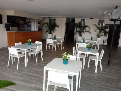 a dining room with white tables and white chairs at Hotel Libano in San Francisco de Macorís