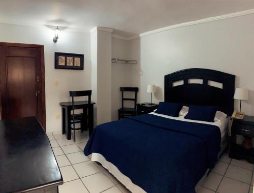 a bedroom with a blue bed and a table and chairs at Hotel Libano in San Francisco de Macorís