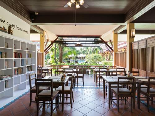 a restaurant with tables and chairs and bookshelves at Le Piman Resort in Rawai Beach