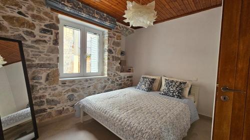 a bedroom with a bed and a stone wall at Summerstone Cottage in Aliveri