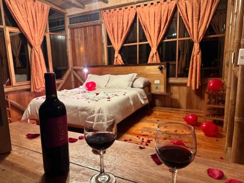 a room with two glasses of wine and a bed at Shua Kasi Mindo in Mindo