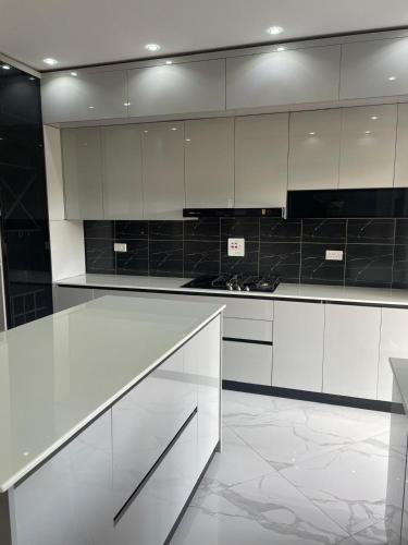 a white kitchen with white cabinets and black appliances at Sunset Grove in Pakwach East
