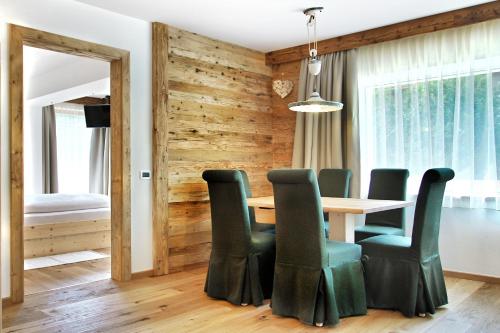 a dining room with a table and green chairs at La Bercia Alpine Lodge & Spa in La Villa