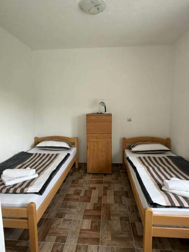 two beds in a room with a wooden cabinet at Apartman Riverside Ripač in Ripač