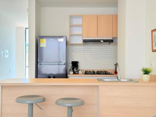 a kitchen with a stainless steel refrigerator and two stools at Exclusivo Apartamento Céntrico con Terraza Privada in Sogamoso