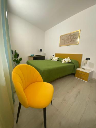 a bedroom with a green bed and a yellow chair at Casa Piazzetta in Saluzzo