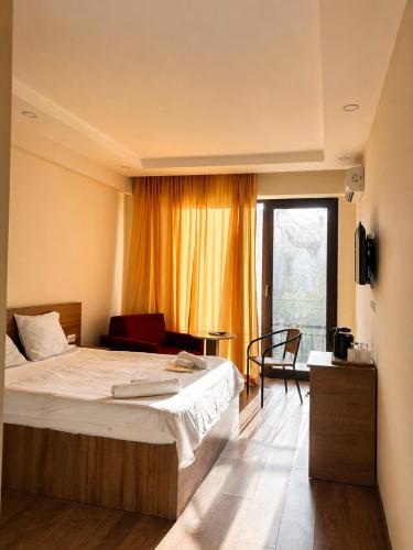 a bedroom with a bed and a chair and a window at Chill Kobuleti in Kobuleti