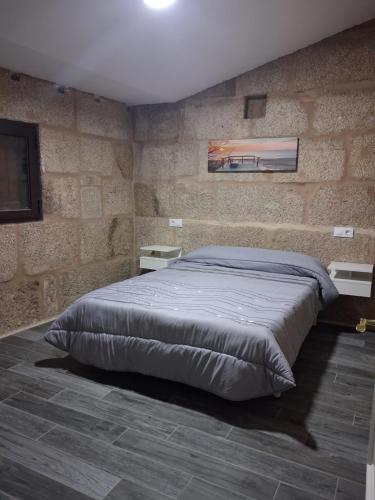 a bedroom with a large bed in a stone wall at Casa YaraMaya in Carballino