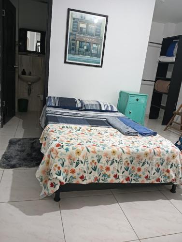 a bedroom with a bed with a flowered blanket on it at APARTAMENTOS Don GUILLE in Santa Rosa de Cabal