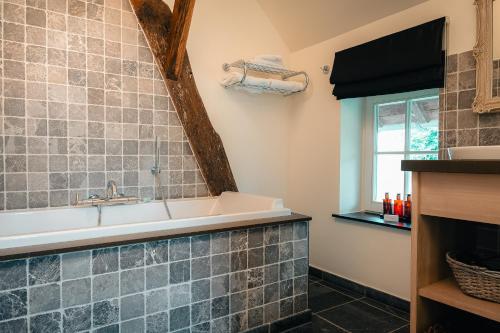 a bathroom with a tub and a sink and a window at Domein Fonteinhof B&B in Borgloon