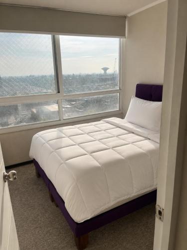 a bed in a room with a large window at Plaza Cervante II in Santiago