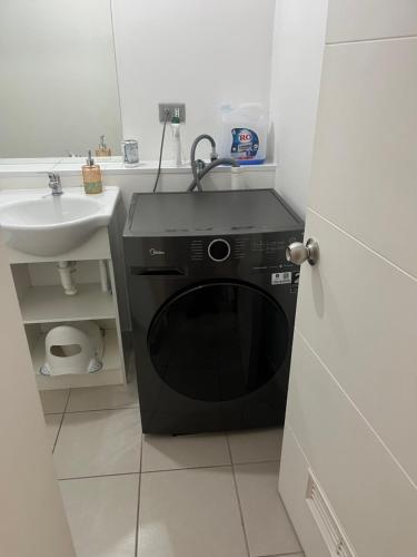 a black washing machine in a bathroom with a sink at Plaza Cervante II in Santiago