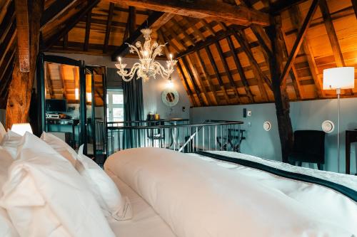 a bedroom with a large white bed with a chandelier at Domein Fonteinhof B&B in Borgloon