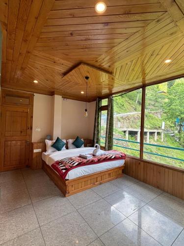 a bedroom with a large bed in a room with windows at Venky's Shoja in Jibhi