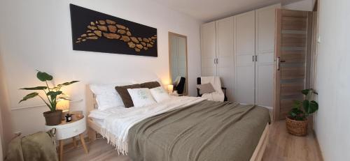 a bedroom with a large bed with white sheets and pillows at Zielone Okno Apartament w Augustowie blisko jeziora i centrum in Augustów