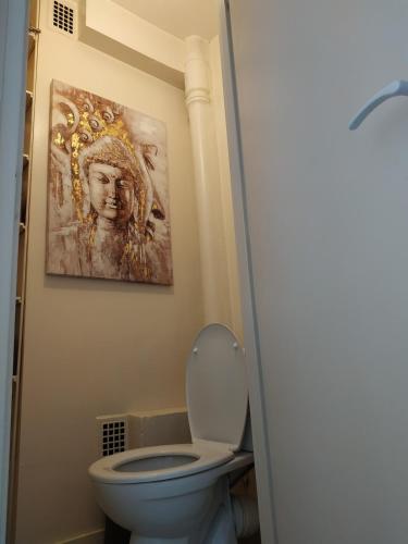 a bathroom with a toilet and a painting on the wall at Studio cosy proche plage & centre in Le Havre
