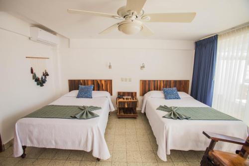 a room with two beds and a ceiling fan at Hotel Rosita in Puerto Vallarta
