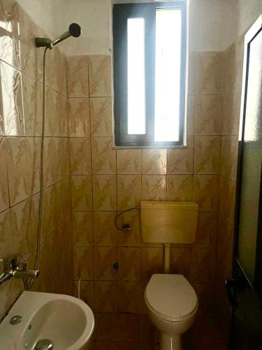 a bathroom with a toilet and a sink and a window at Mani rooms in Durrës