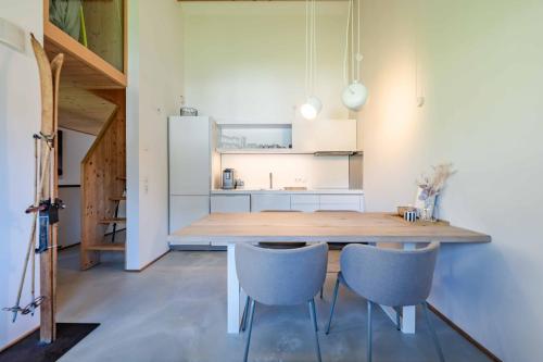 a kitchen with a wooden table and two blue chairs at hus9 in Mittelberg
