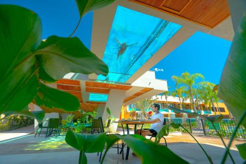 a man sitting at a table on a patio at Arte da Natureza Hotel Bonito in Bonito