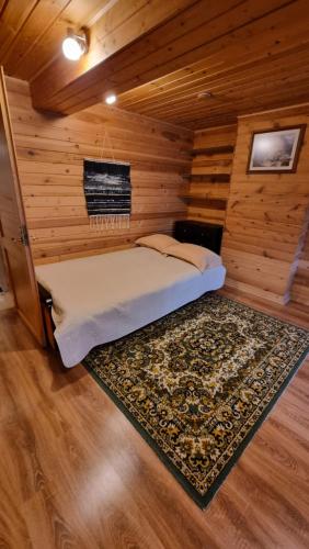 a bed in a wooden room with a rug at Дом у моря in Suurupi