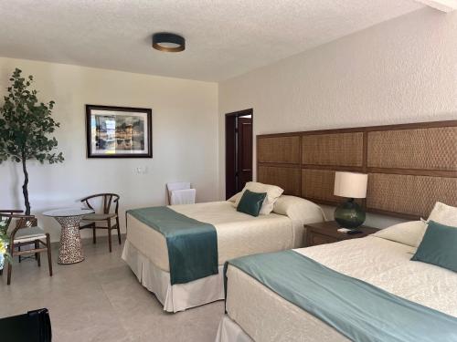 a hotel room with two beds and a table at Hotel Boutique Casa Ceibas in Cuautla Morelos