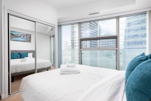 a bedroom with a white bed and a large window at Downtown Toronto CN tower Condo in Toronto