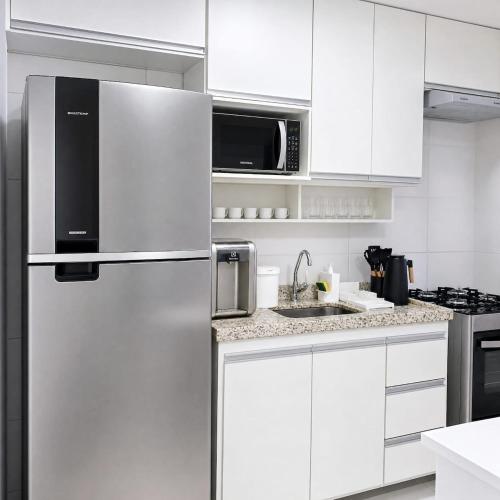 a kitchen with white cabinets and a refrigerator at Apto com ar e piscina próximo a Cabo Frio e Arraial do Cabo in São Pedro da Aldeia