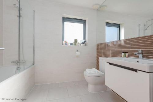 a bathroom with a toilet and a sink and a tub at Little Spinney in Dorchester