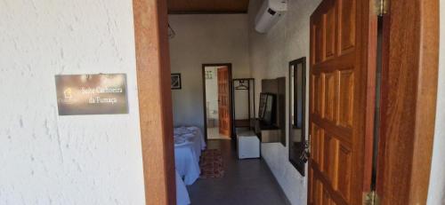 a hallway with a room with a table and a door at Chalés e Suítes Campos de São João in Palmeiras