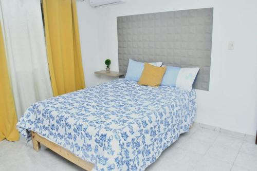 a bedroom with a bed with a blue and white comforter at Vacacional rent in Boca Chica