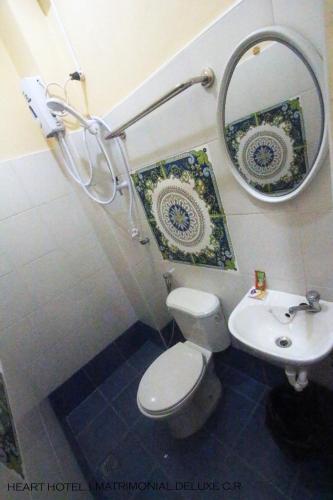 a bathroom with a toilet and a mirror and a sink at Heart Hotel and Services in Dumaguete