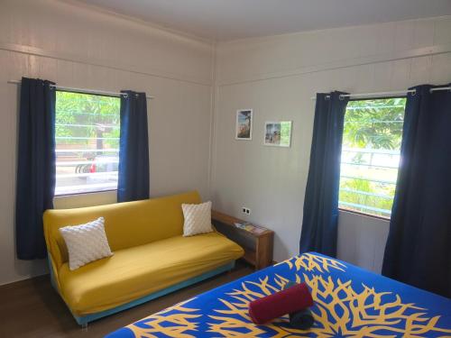 a living room with a yellow couch and a bed at Bora Bora Vairupe lodge in Bora Bora