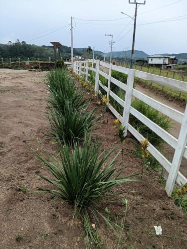 a white fence in a field with some plants at Recanto do SOL in Imaruí