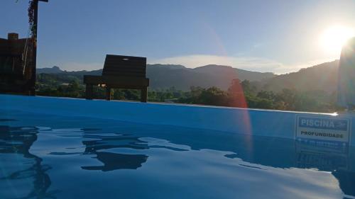 a pool with a chair sitting next to the mountains at Recanto do SOL in Imaruí