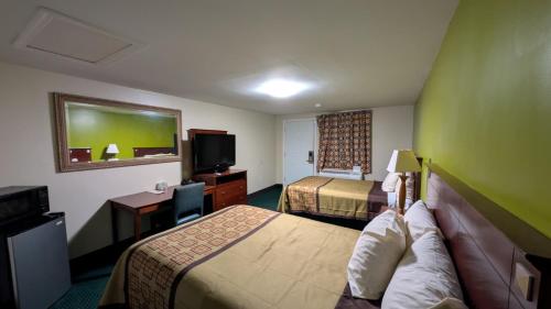 a hotel room with two beds and a desk and a television at Slumberland Motel Mount Holly in Mount Holly