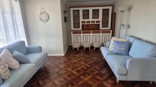 a living room with blue couches and a wooden floor at Cassana In The Cove in North Arms Cove