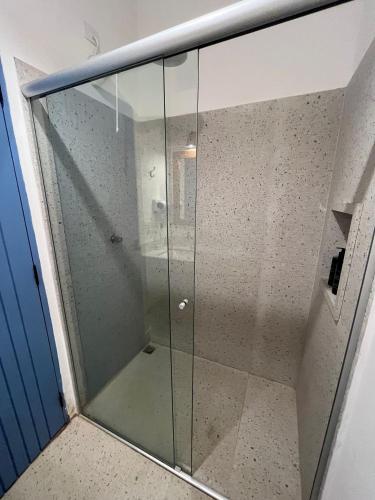 a glass shower in a room with a blue door at Villa Tennis in Ubatuba