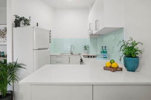 a white kitchen with a bowl of fruit on a counter at Avalon Beachside Apartment Pool Beach Access in Avalon